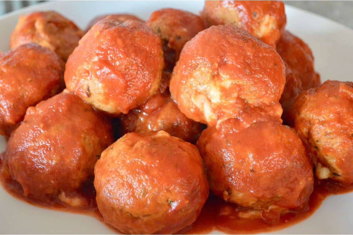 stack of stuffed turkey meatballs with marinara sauce on a white plate. 