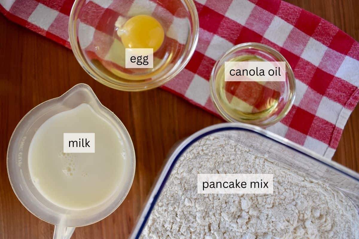 overhead photo of ingredients need to prepare recipe including milk, egg, oil, and dry pancake mix. 