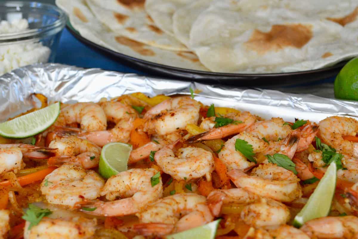 Sheet Pan Shrimp Fajitas on a pan with tortillas in the background. 