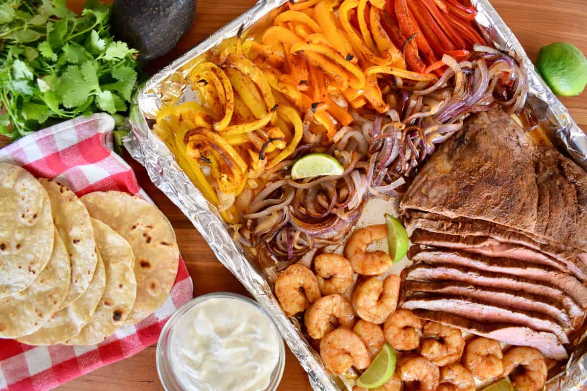 overhead photo of steak and shrimp fajitas with the steak cut into long strips and bell peppers next to it. 