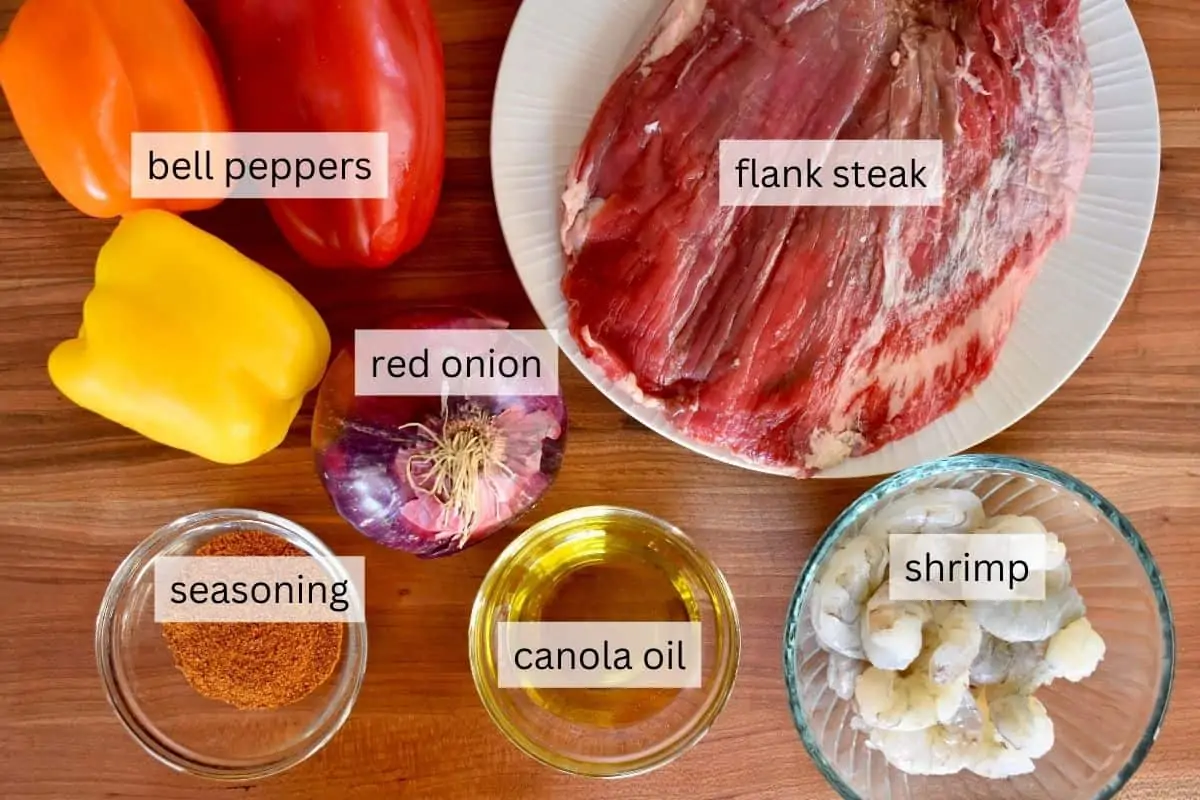 overhead photo of ingredients on a wood countertop including peppers, onions, and taco seasoning. 