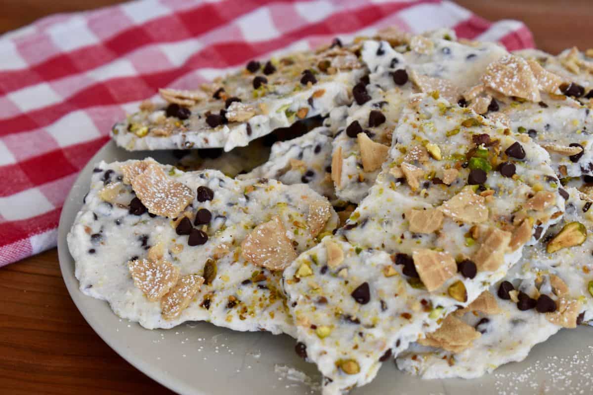Frozen Cannoli Bark on a plate with a checkered napkin in the background. 
