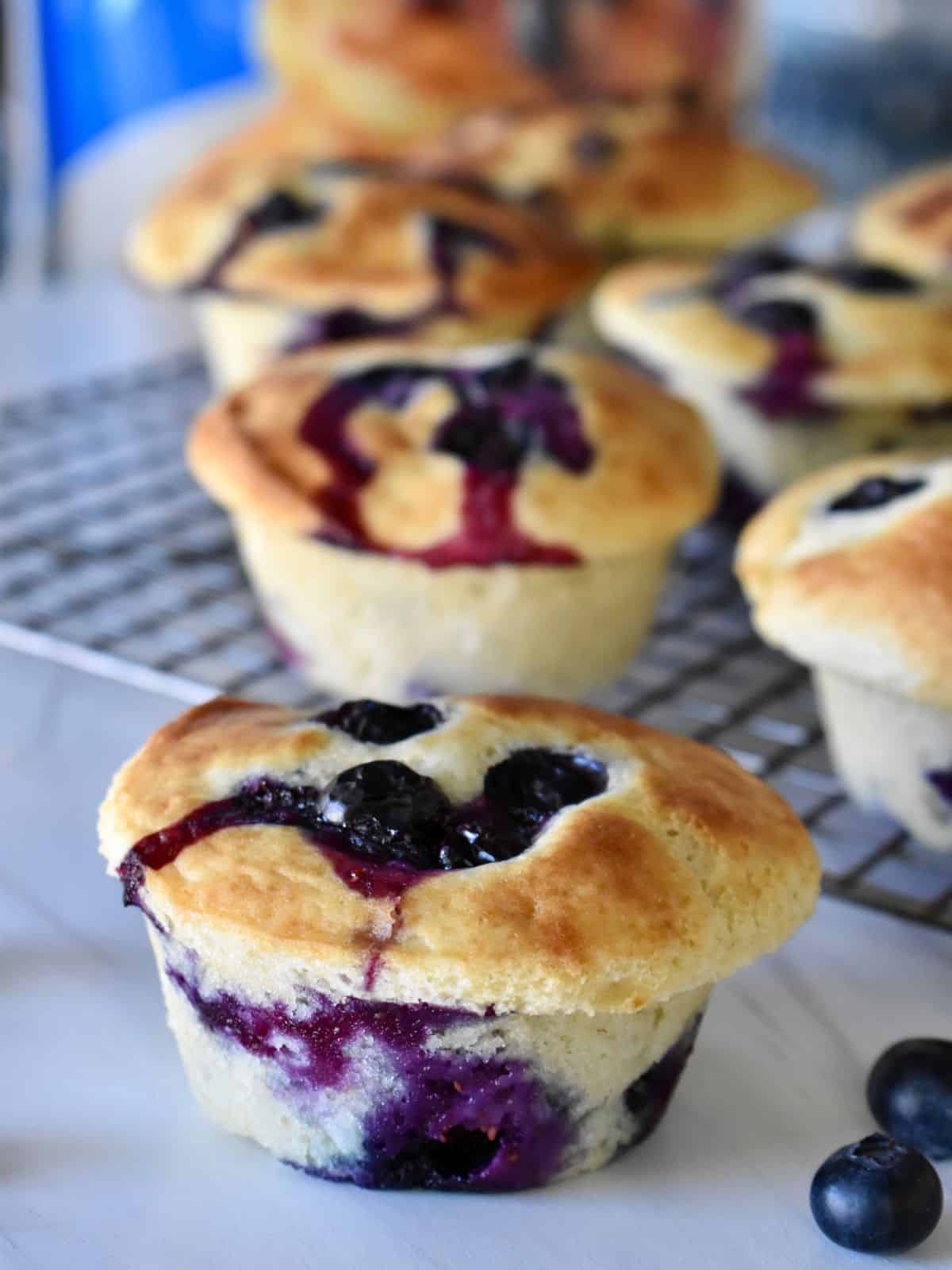 Blueberry Pancake Mix Muffins on a wire rack with a store-bought pancake mix bag in the background. 