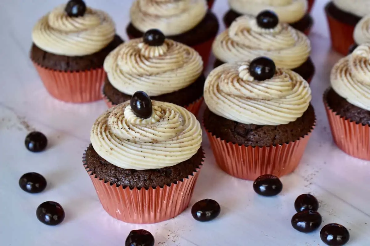 Espresso Cupcakes on a white countertop with chocolate covered espresso beans. 