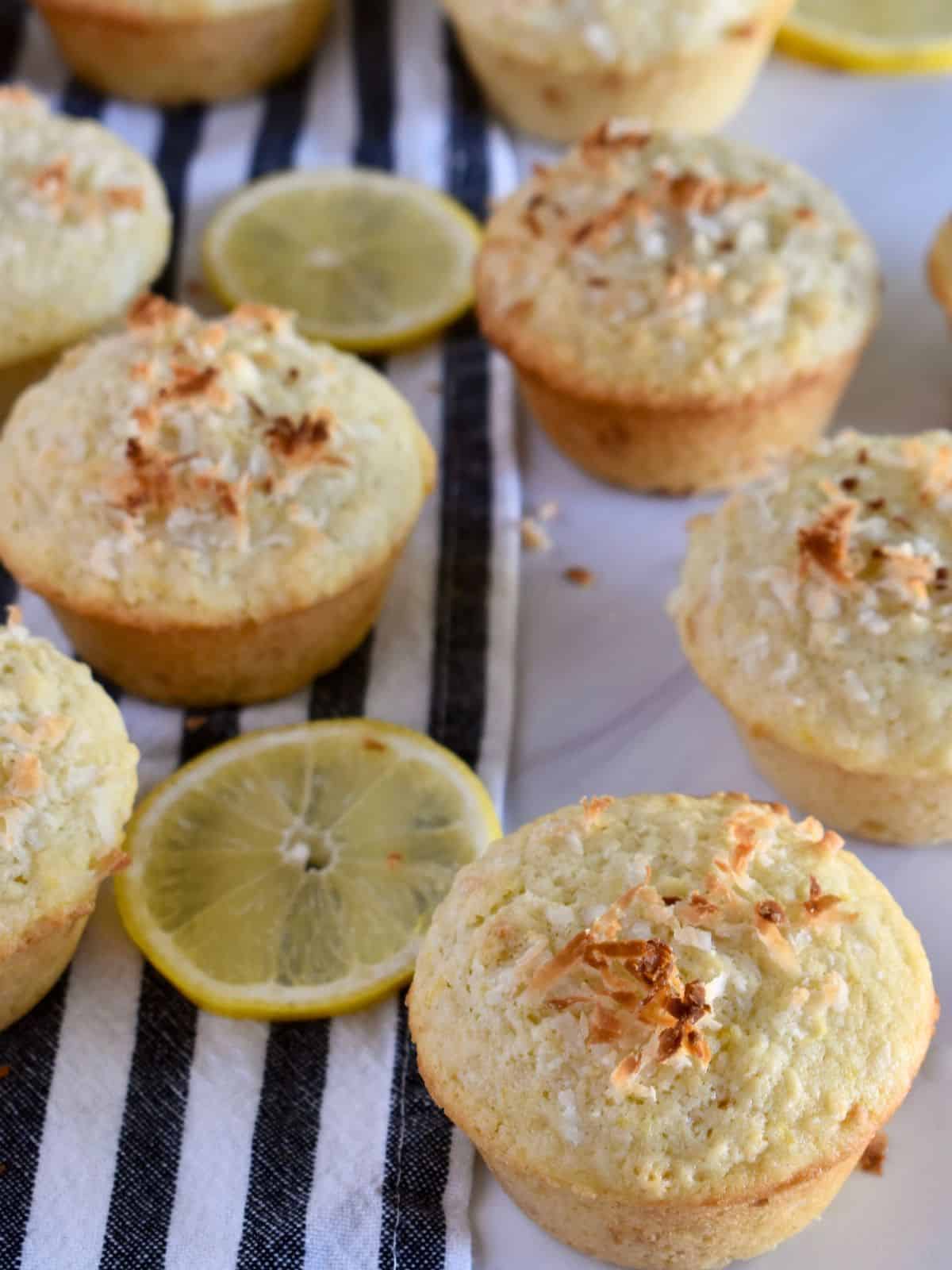 Lemon coconut muffins recipe on a stripped towel with slices of lemon. 