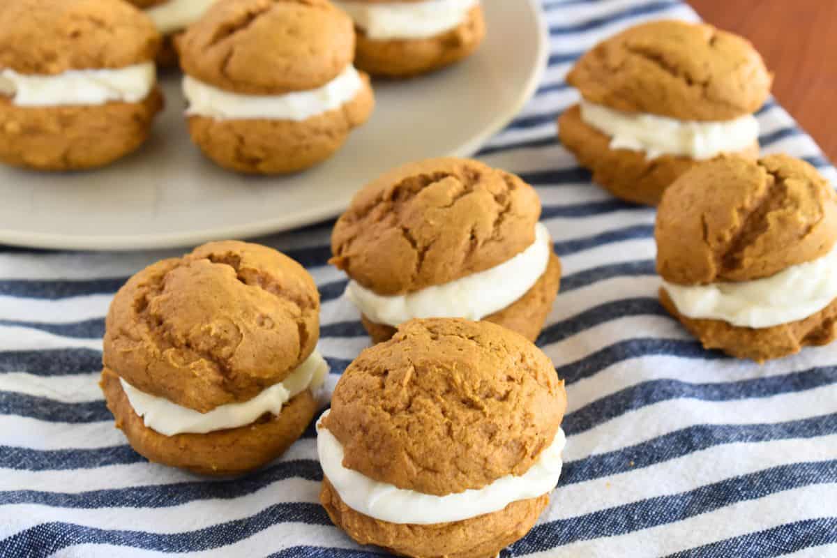 Pumpkin Whoopie Pies with Cake mix stacked on each other on a striped napkin. 
