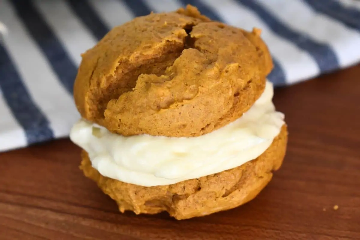 Close up of a single pumpkin whoopie pie on a wood countertop. 