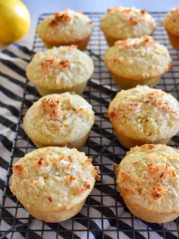 Lemon Coconut Muffins on a wire cooling rack with a lemon in the background.