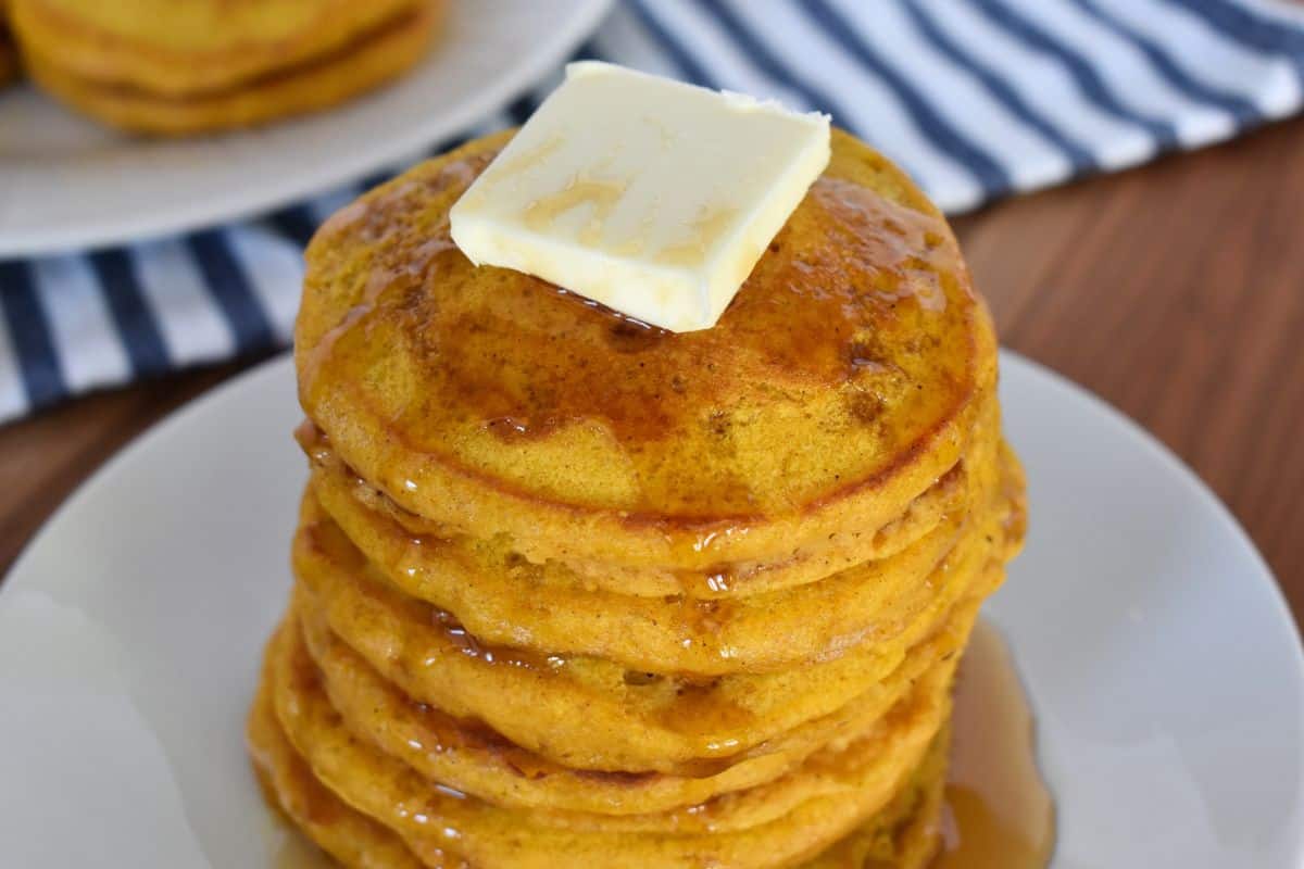 Pumpkin pancakes with pancake mix on a white plate with a striped napkin in the background. 