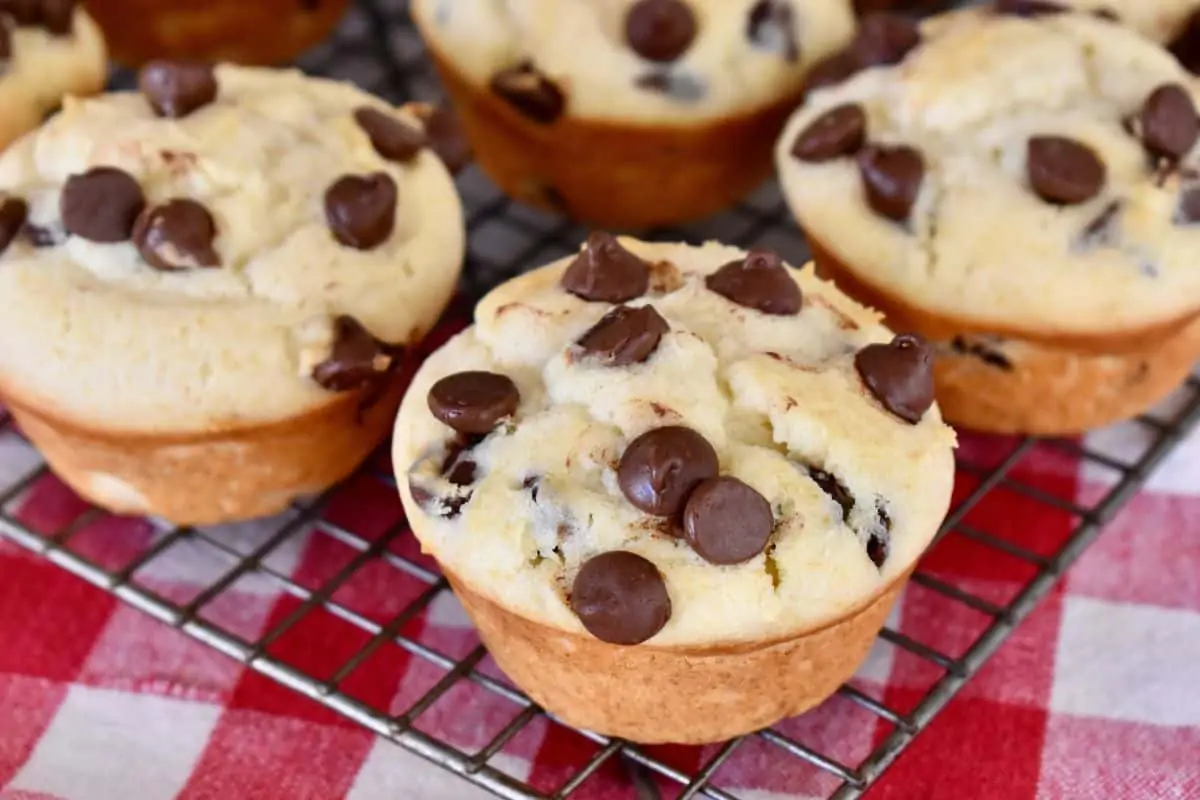 Chocolate Chip Ricotta Muffins on a wire cooling rack with a checkered napkin underneath. 
