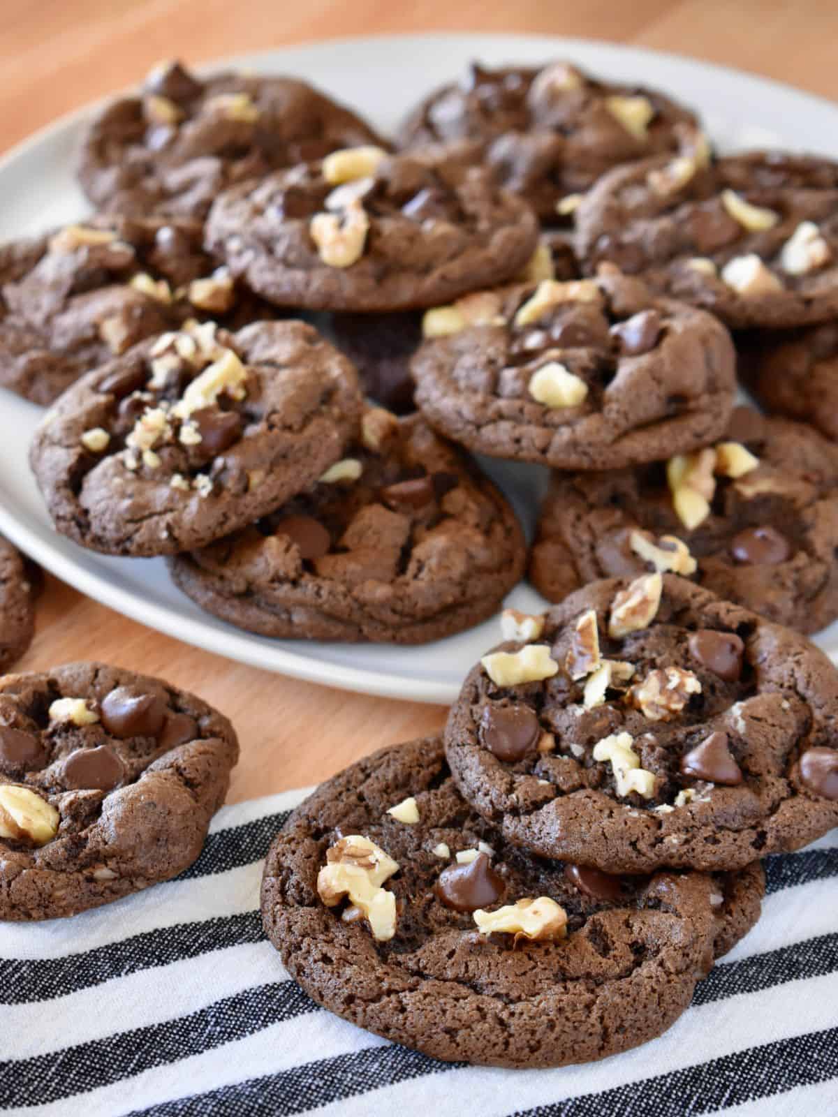 Chocolate Walnut Cookies on a white plate with a striped napkin underneath. 