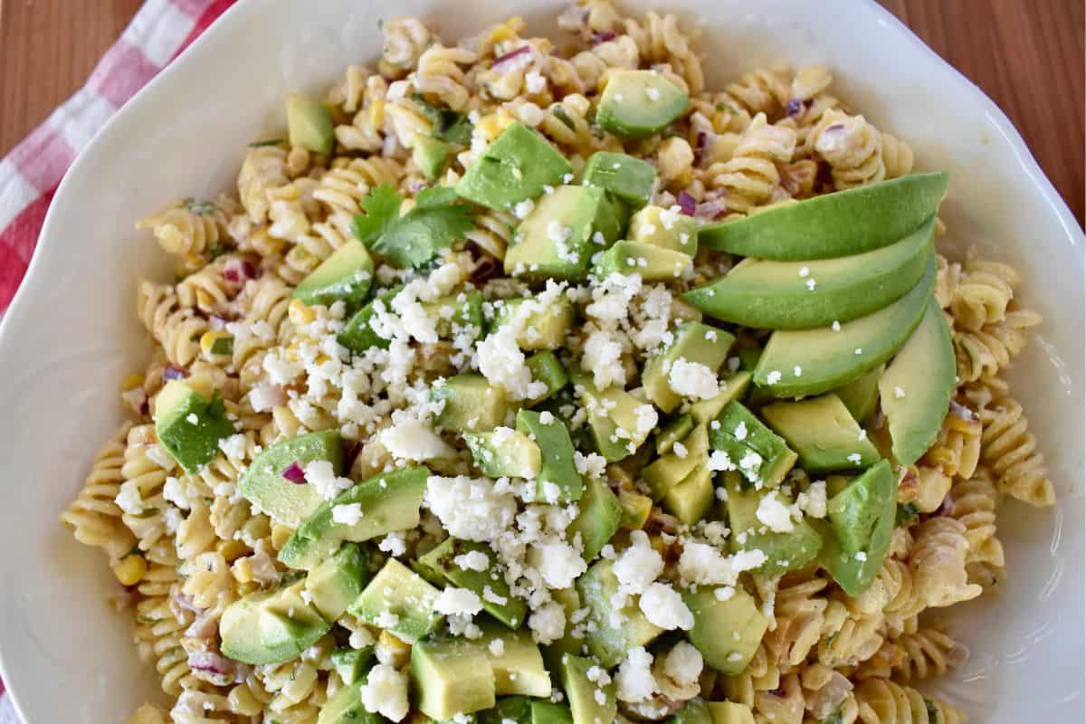 Overhead photo of elote pasta salad with avocado and cotija cheese on top. 