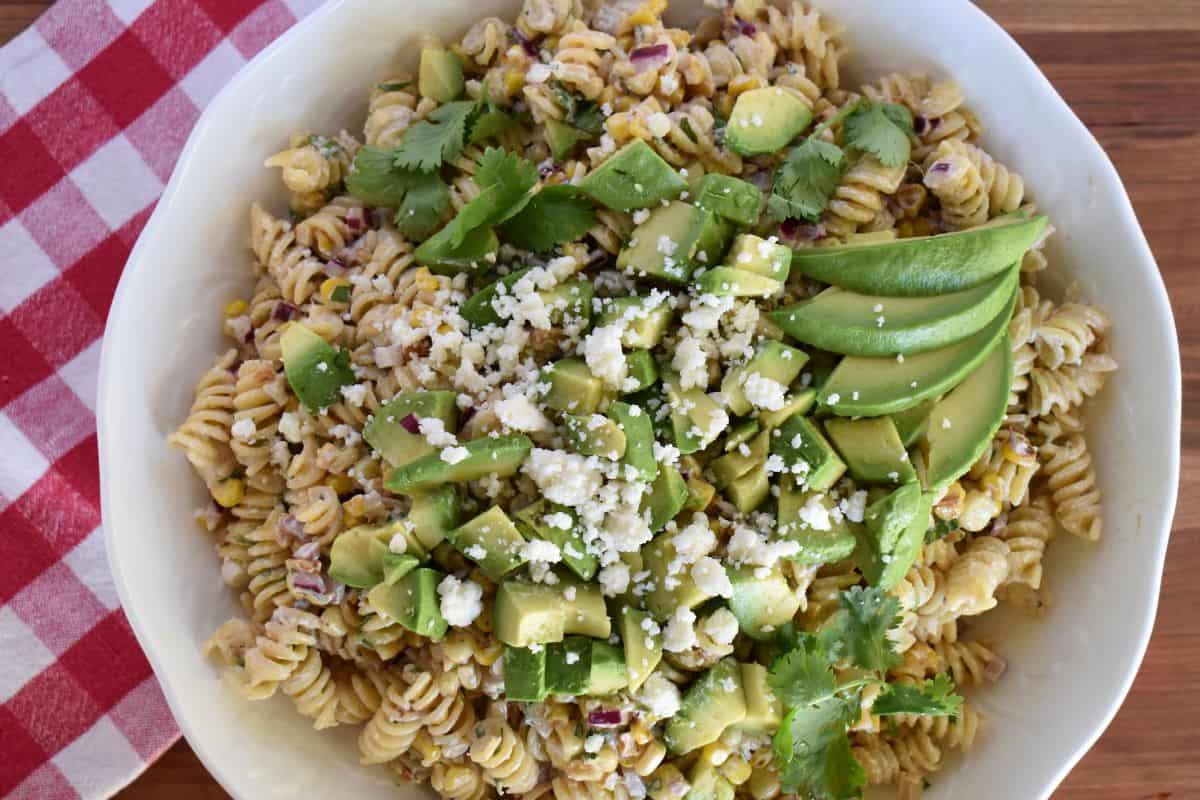 Elote Pasta Salad in a white bowl with a checkered napkin underneath. 