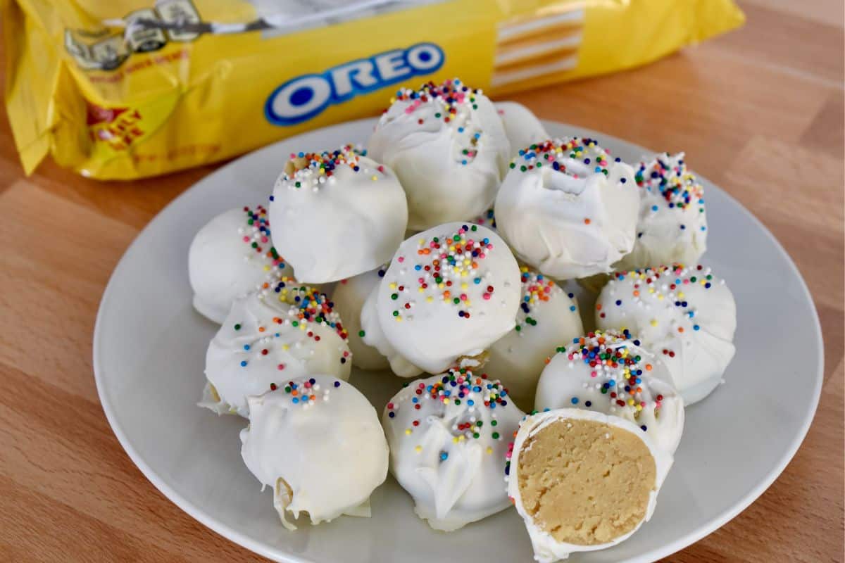 Golden Oreo Truffles on a white plate with oreo package in the background. 