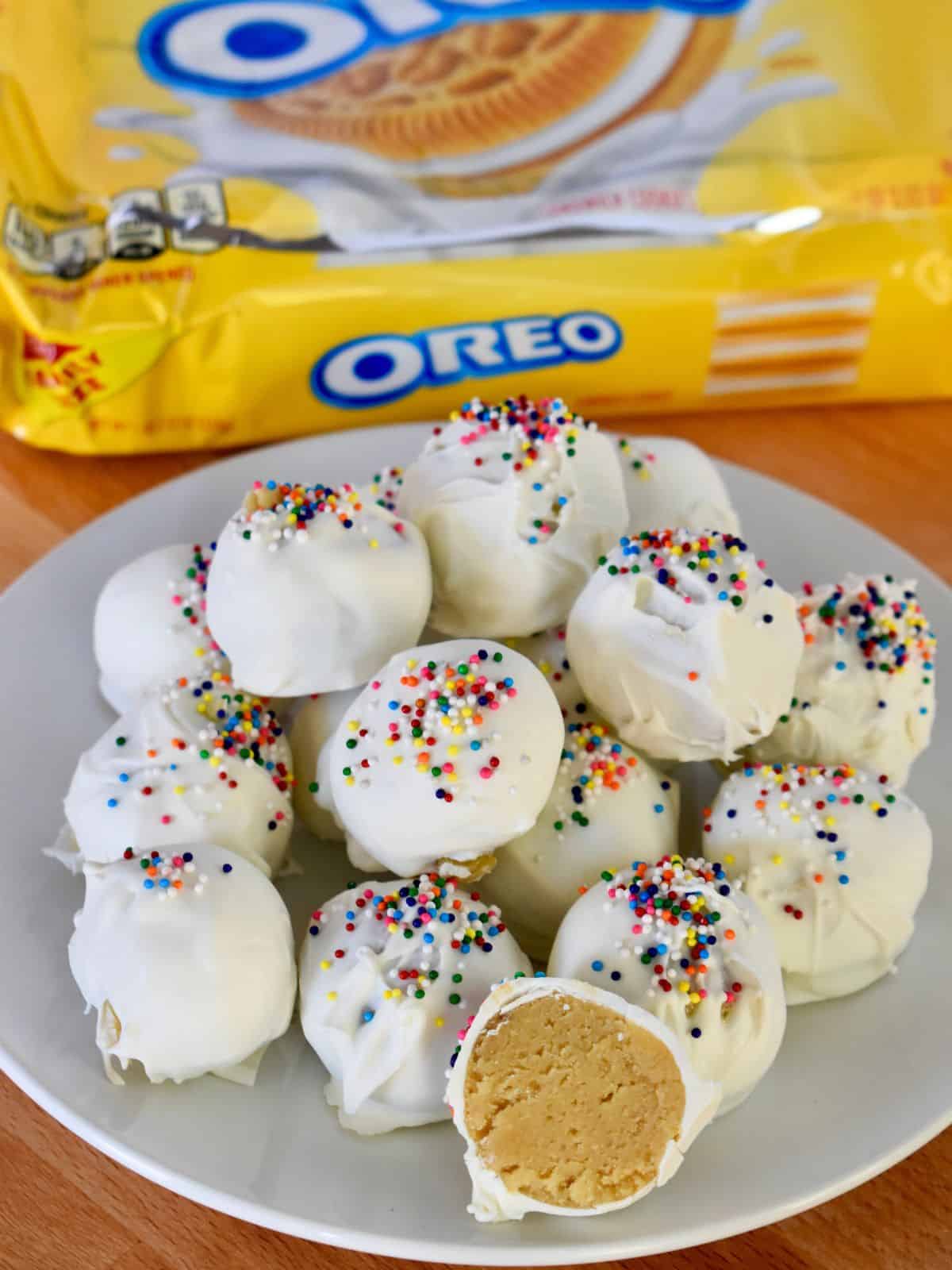 Golden Oreo Truffles on a white plate with a package of Golden Oreos in the background. 