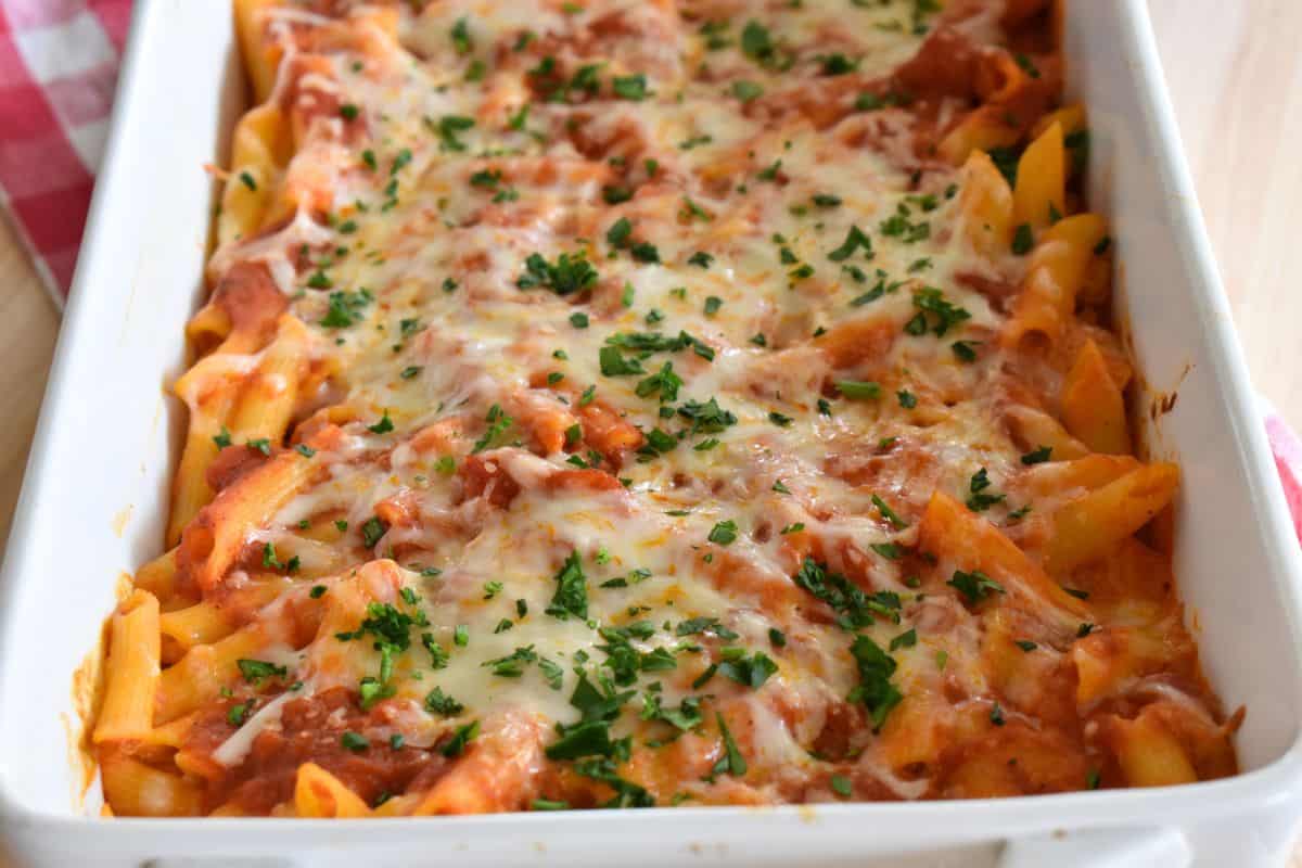 Baked Penne with ricotta in a white casserole dish with parsley sprinkled on top. 