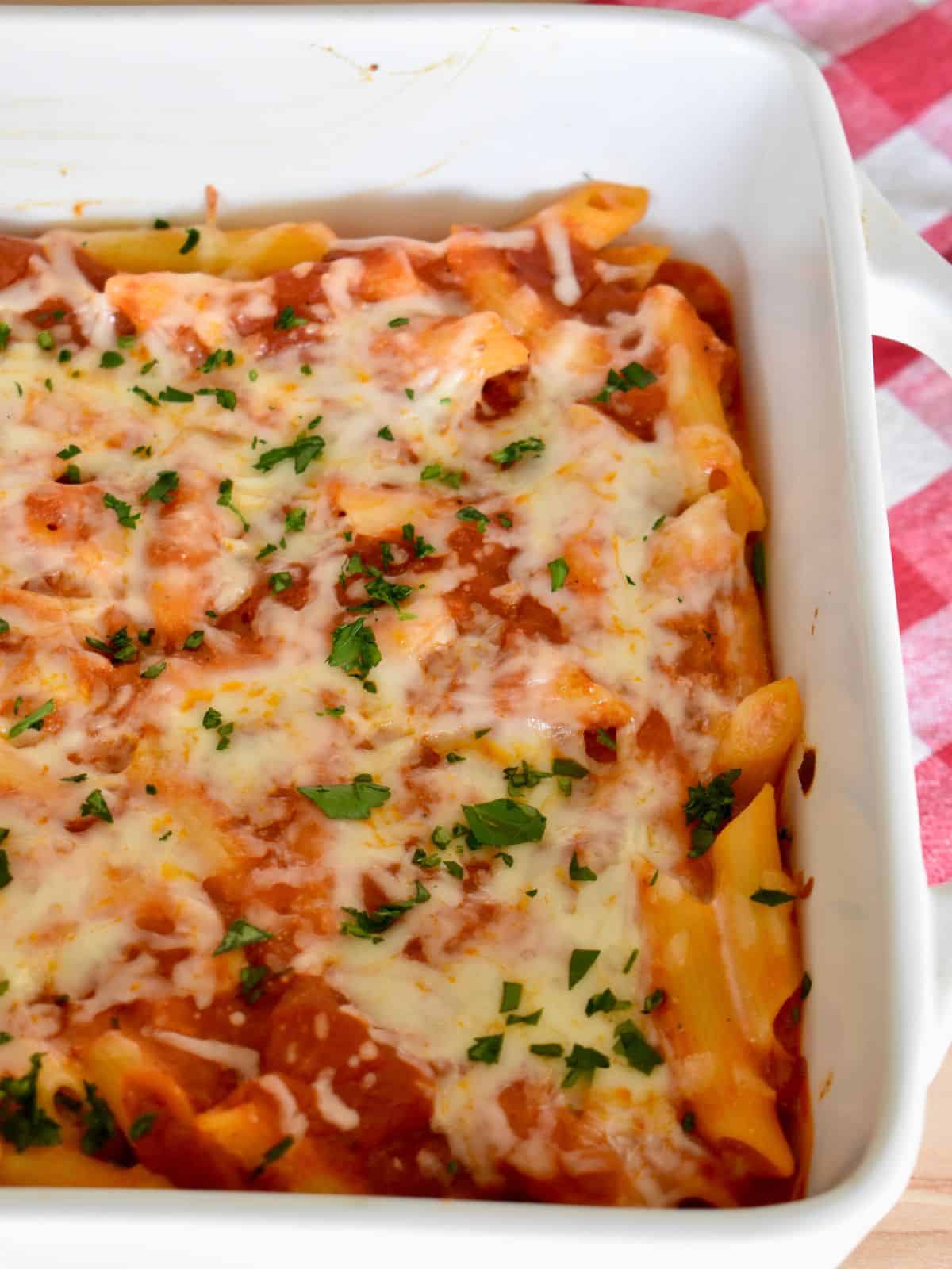 Baked Penne with Ricotta in a white baking dish with chopped parsley sprinkled on top. 