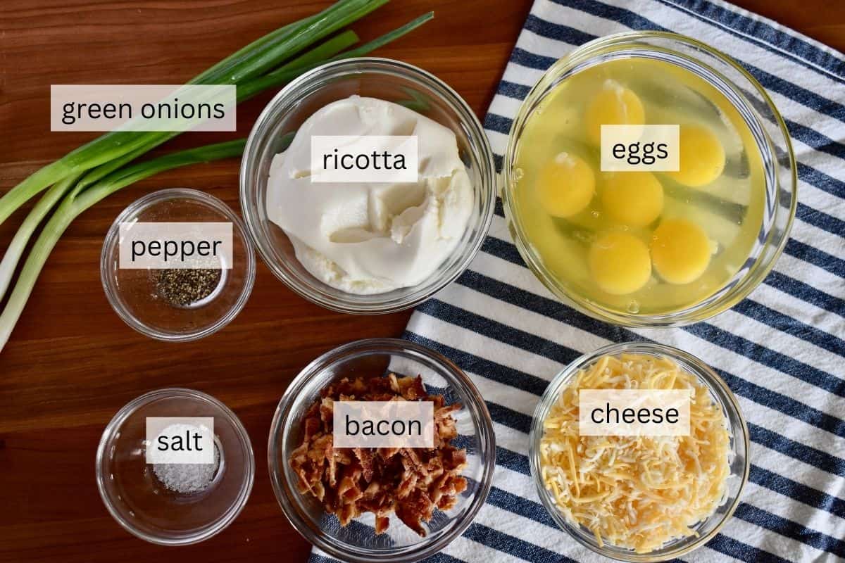 Ingredients for recipe including eggs, cheese, bacon, and green onion. 