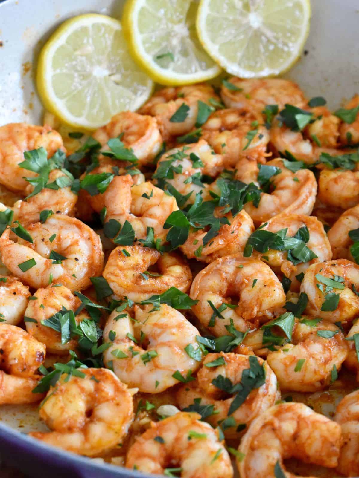 Pan Seared Shrimp with garlic in a pan with lemon slices and parsley on top.
