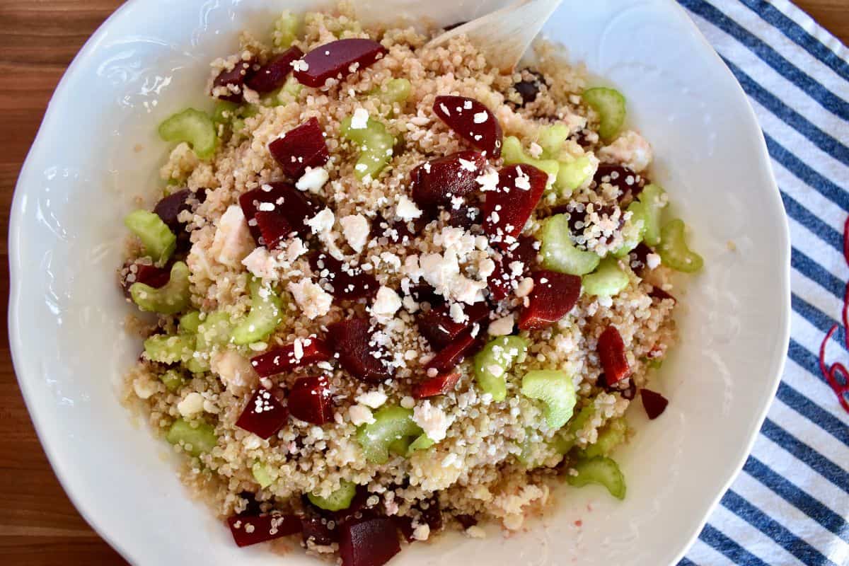 Quinoa Beet salad with red beets, celery, and feta cheese crumbles in a white bowl. 