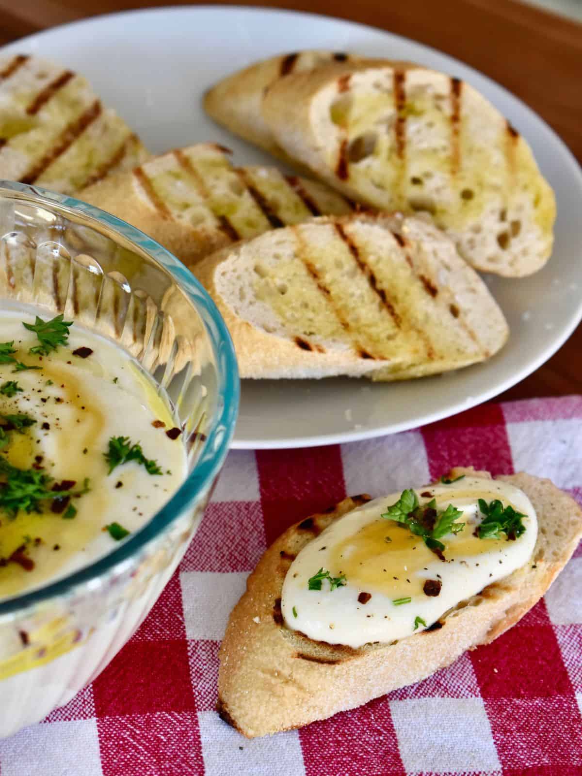 Whipped ricotta dip on a toasted baguette with parsley, red pepper flakes and honey on top. 