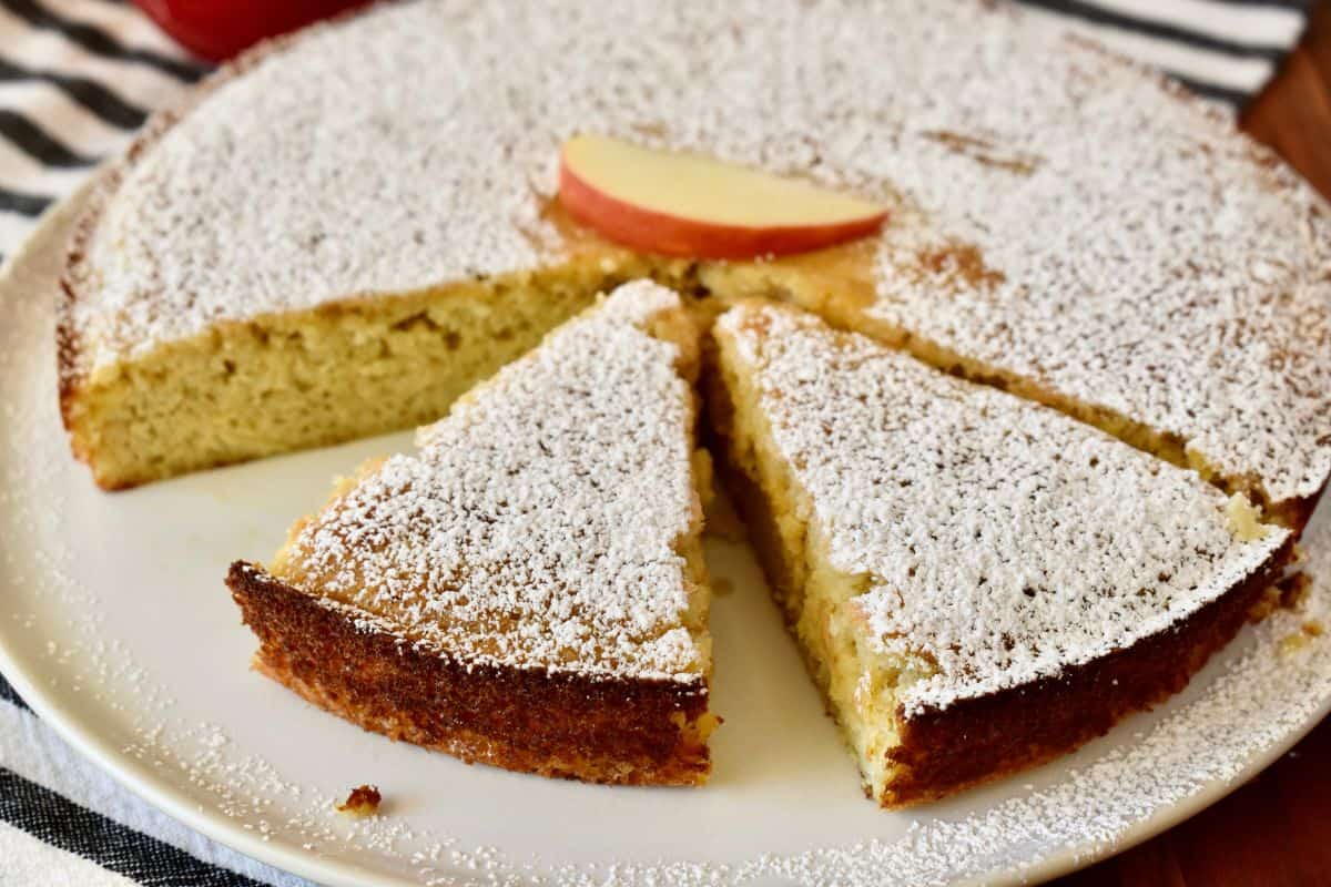 Almond Flour Apple Cake cut into slices on a white plate with powdered sugar sprinkled on top. 