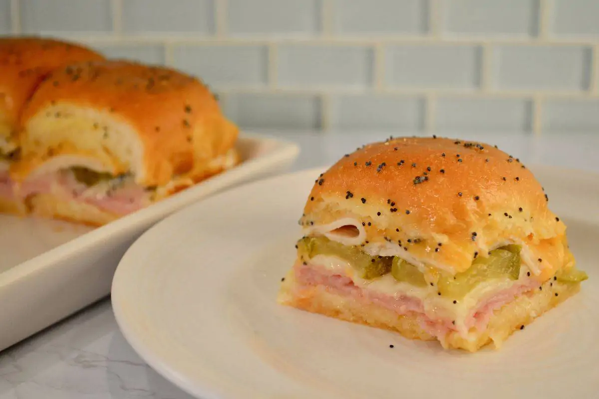 Ham and Cheese Sliders on Hawaiian Rolls with butter and poppyseeds on top. 