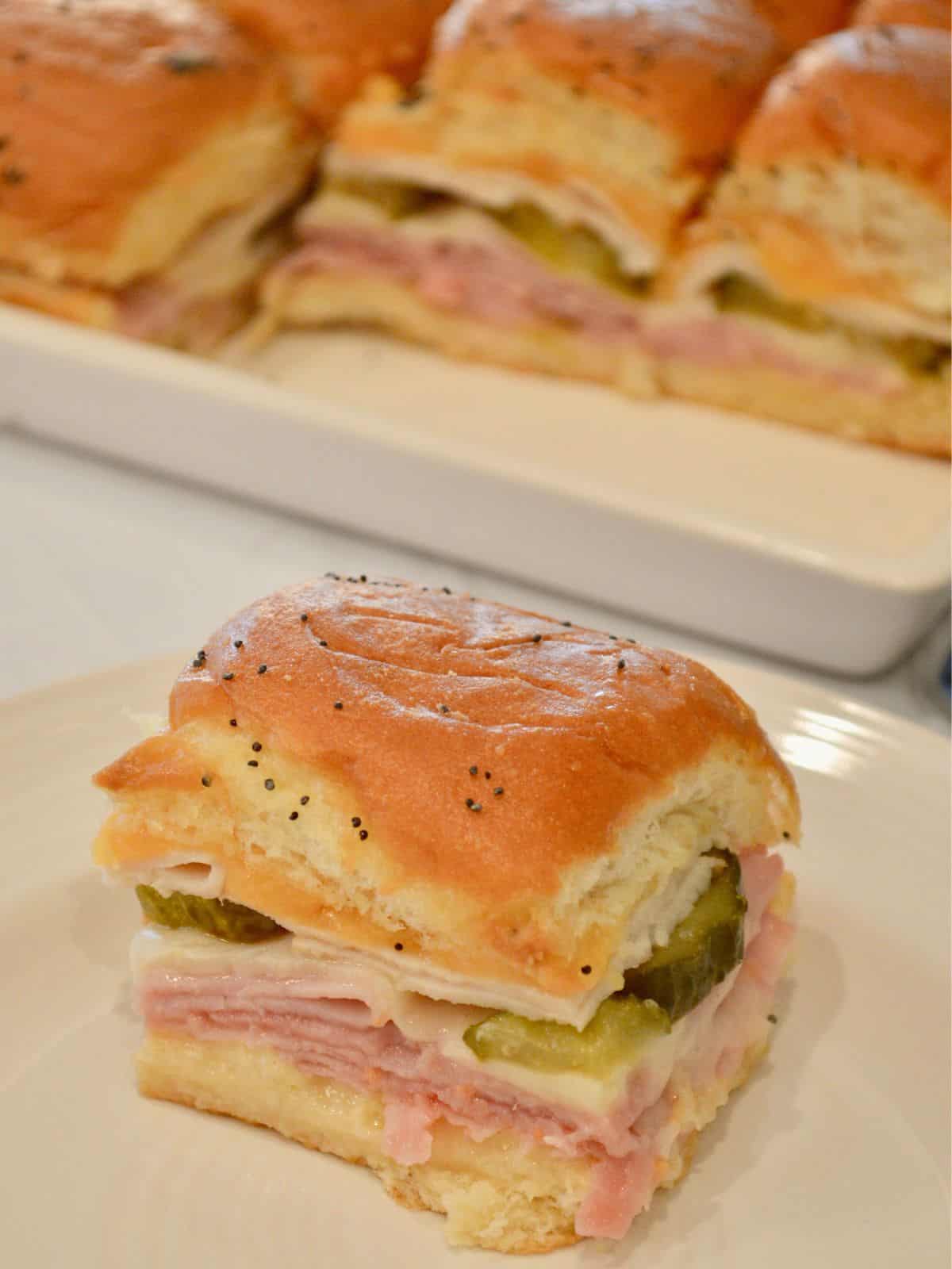Ham and Cheese Sliders on Hawaiian Rolls on a white plate. 