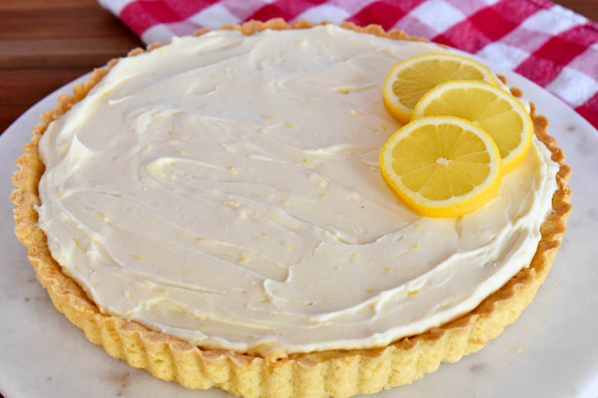 Lemon Mascarpone Tart on a white plate with lemon slices on top. 