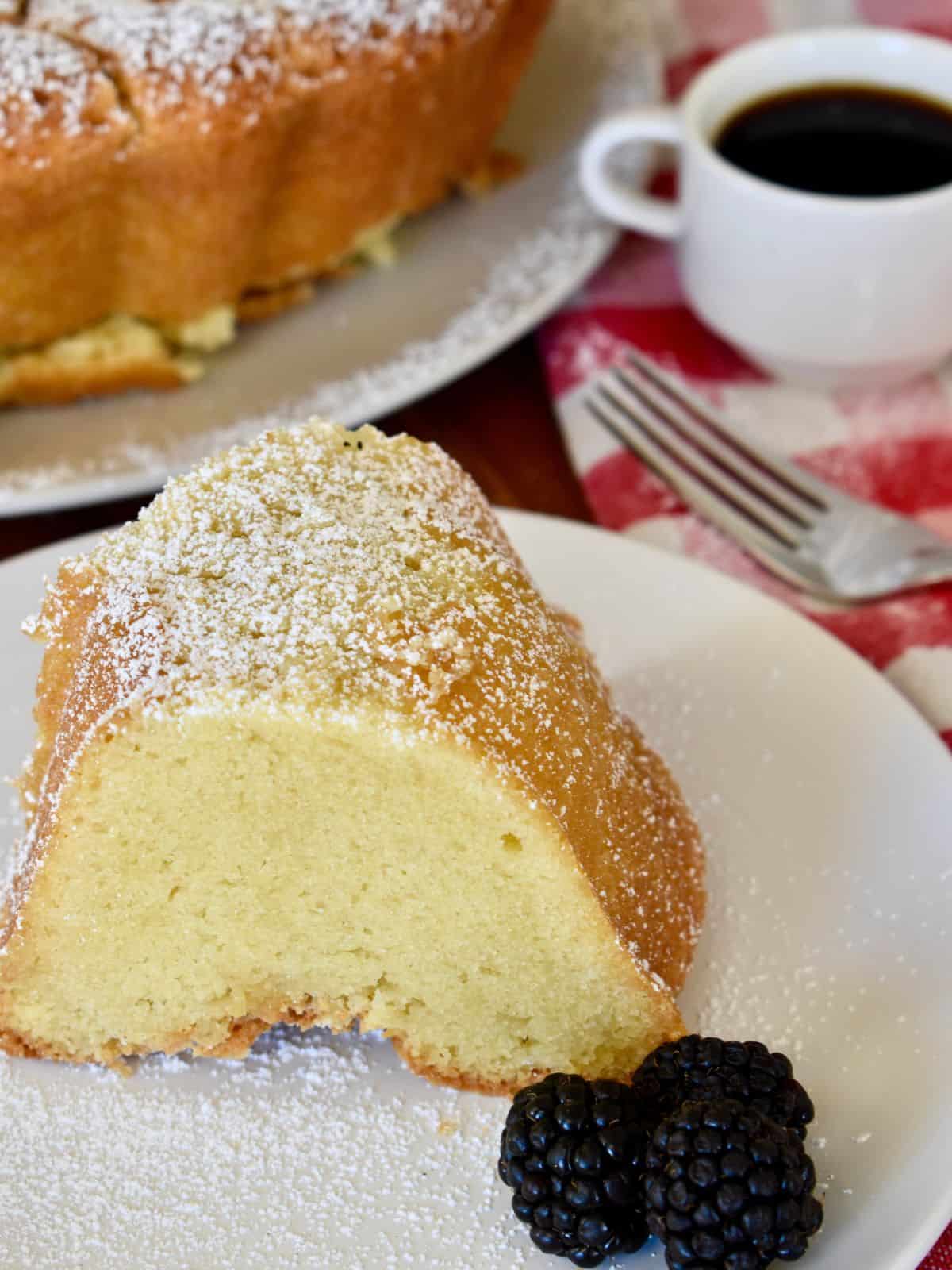 Slice of mascarpone pound cake on a white plate with a fork behind it. 