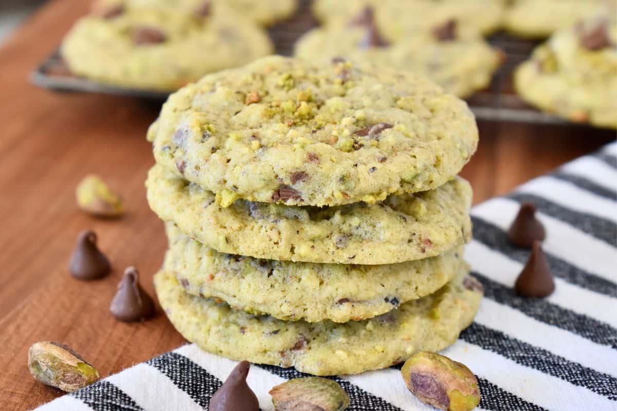 Stack of chocolate chip pistachio cookies on a striped napkin. 