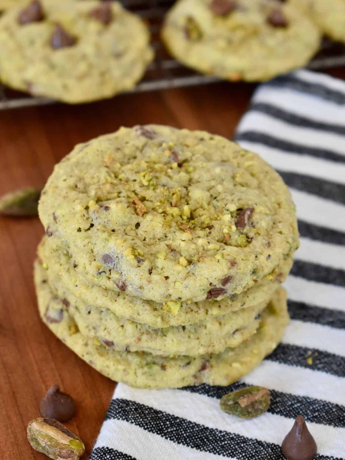 Chocolate chip pistachio cookies stacked on a striped napkin. 