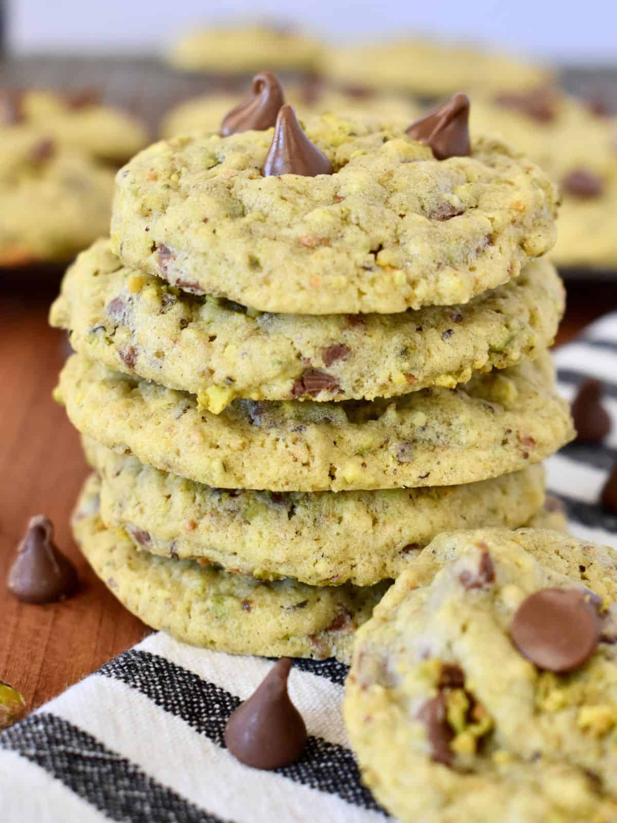 Chocolate Chip Pistachio Cookies stacked on each other on a striped towel. 