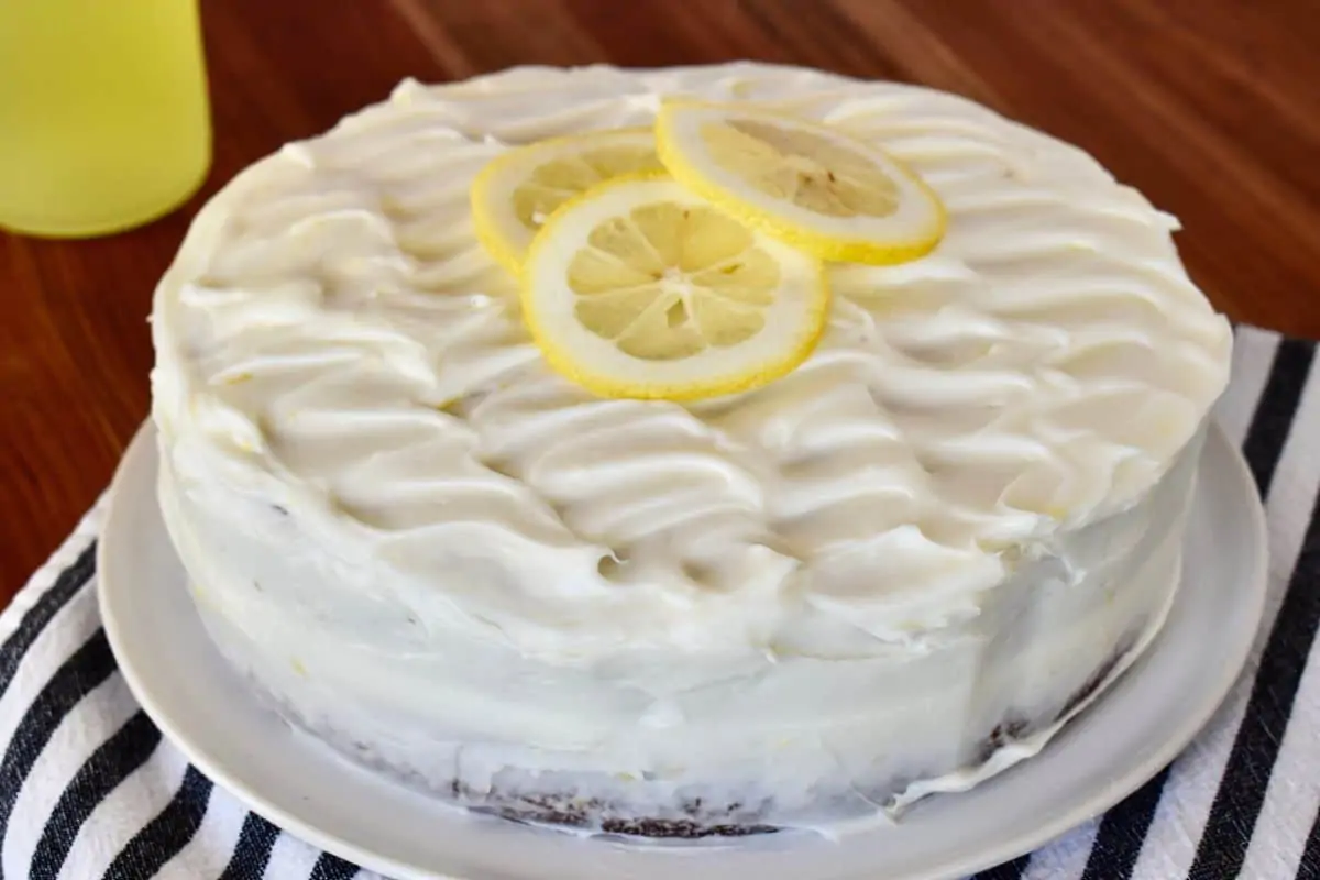 Frosted Limoncello Ricotta Cake with a slice of lemon on top. 