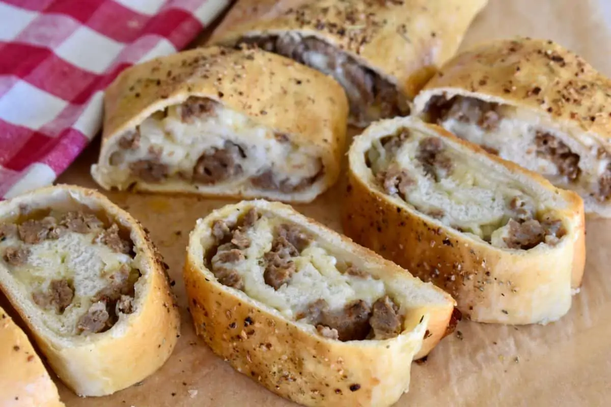 Slices of Italian Sausage Bread on a counter top with a checkered napkin. 