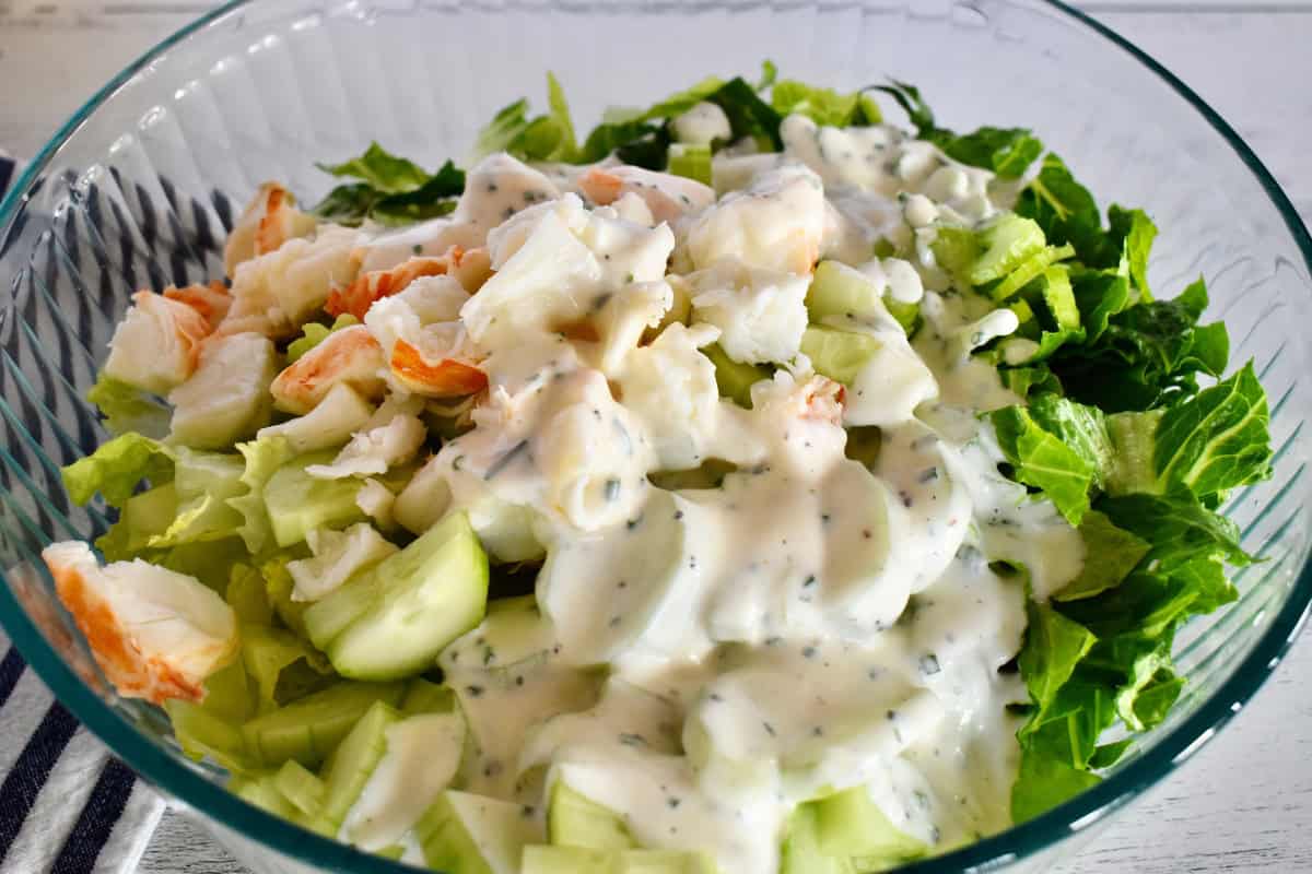 Creamy buttermilk dressing poured on top of the ingredients in a white dish.