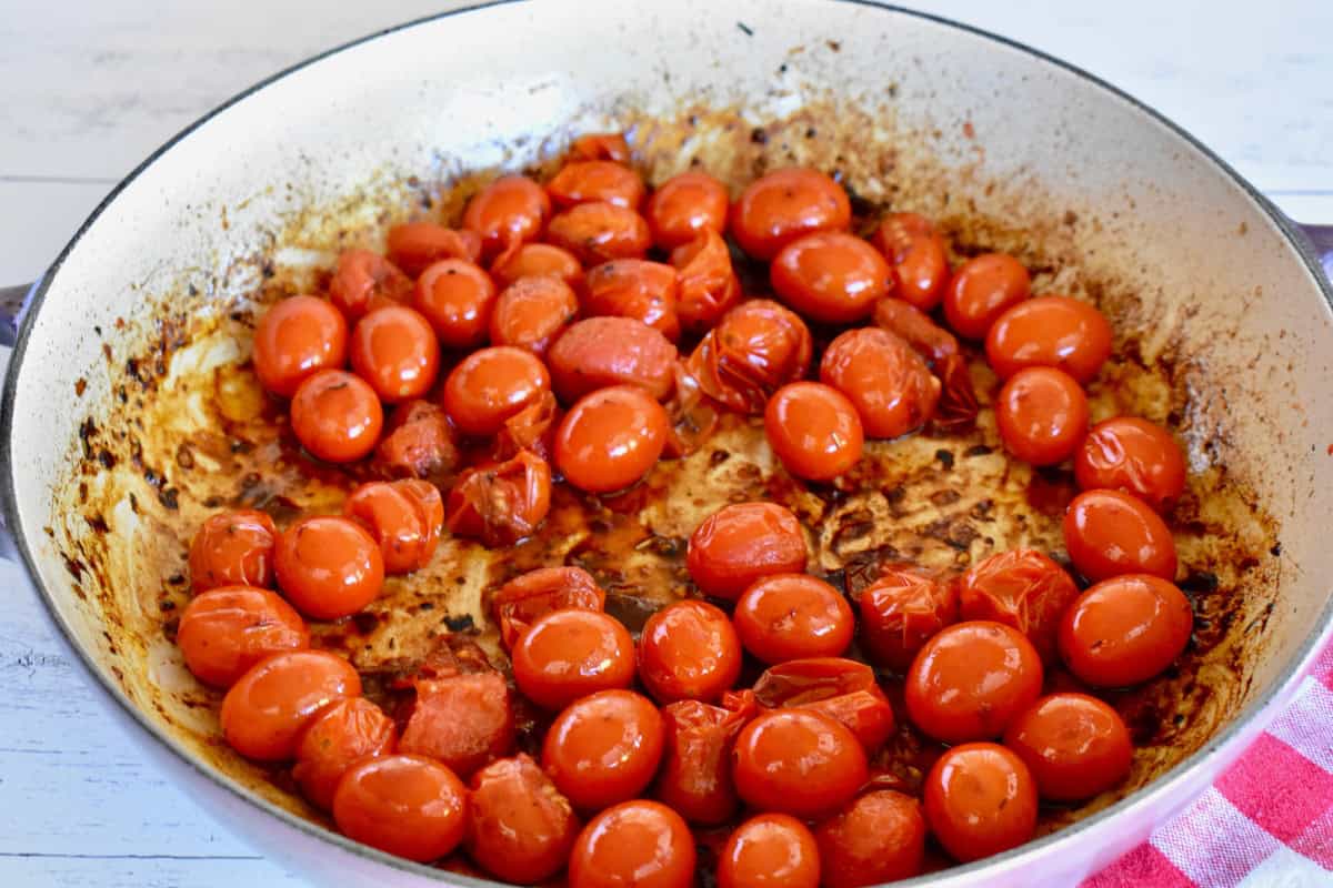 Cherry tomatoes cooking in a large skillet. 