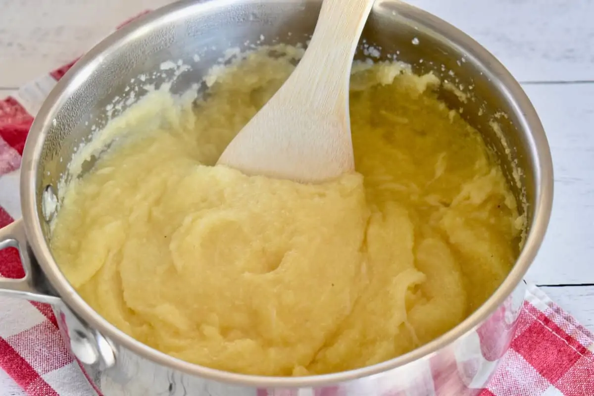 Cooked polenta in a pot with a wooden spoon. 