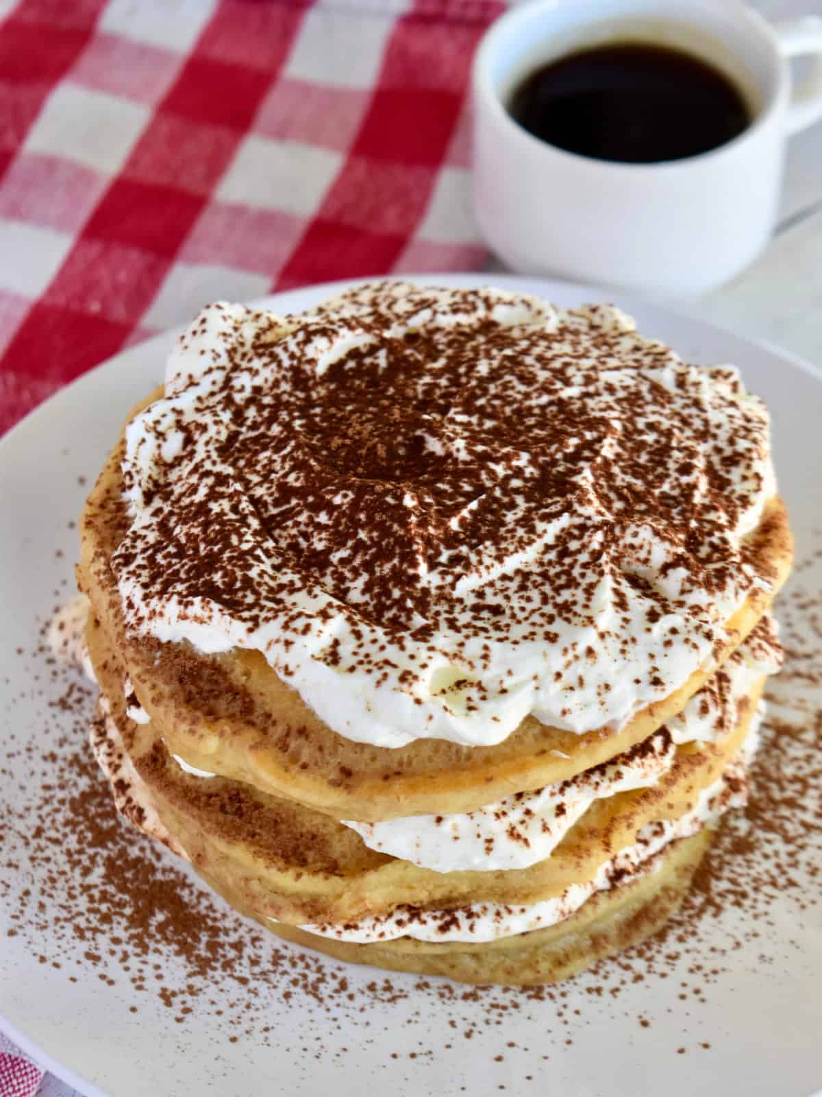 Tiramisu Pancakes stacked on a white plate. 