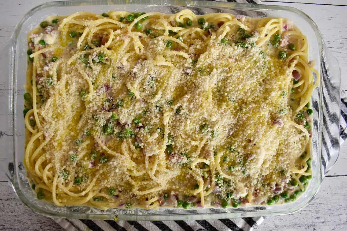 All of the ingredients in a glass baking pan sprinkled with parmesan cheese and a drizzle of olive oil.