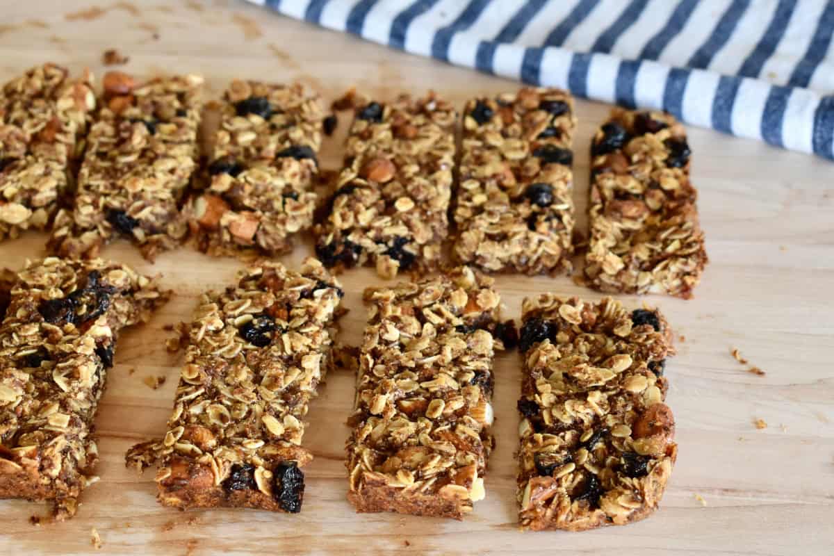 Cranberry Granola Bars with almonds cut into bars on a cutting board.