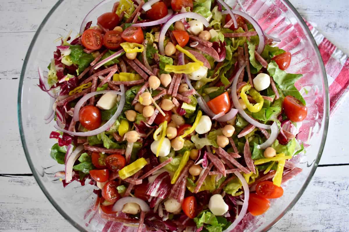 Italian Chopped Salad in a glass bowl with a checkered napkin underneath.