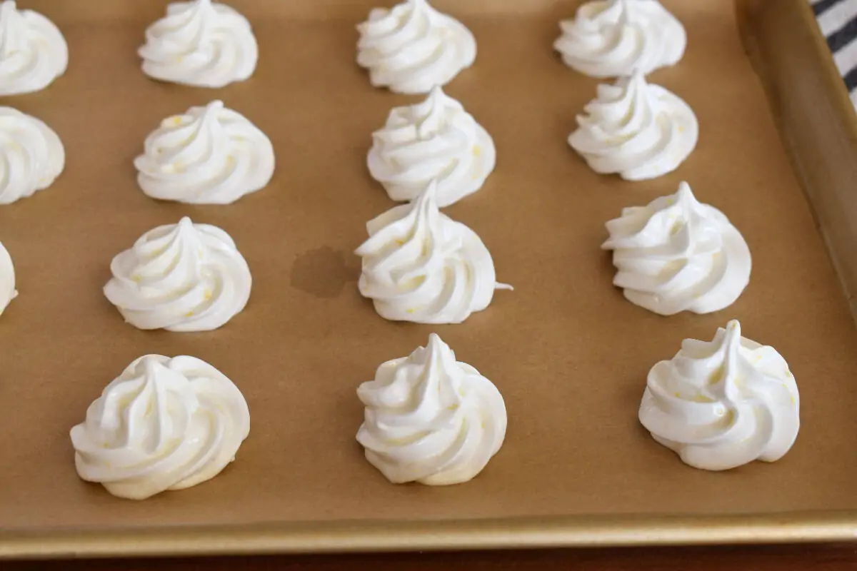 Piped batter on a lined baking sheet.