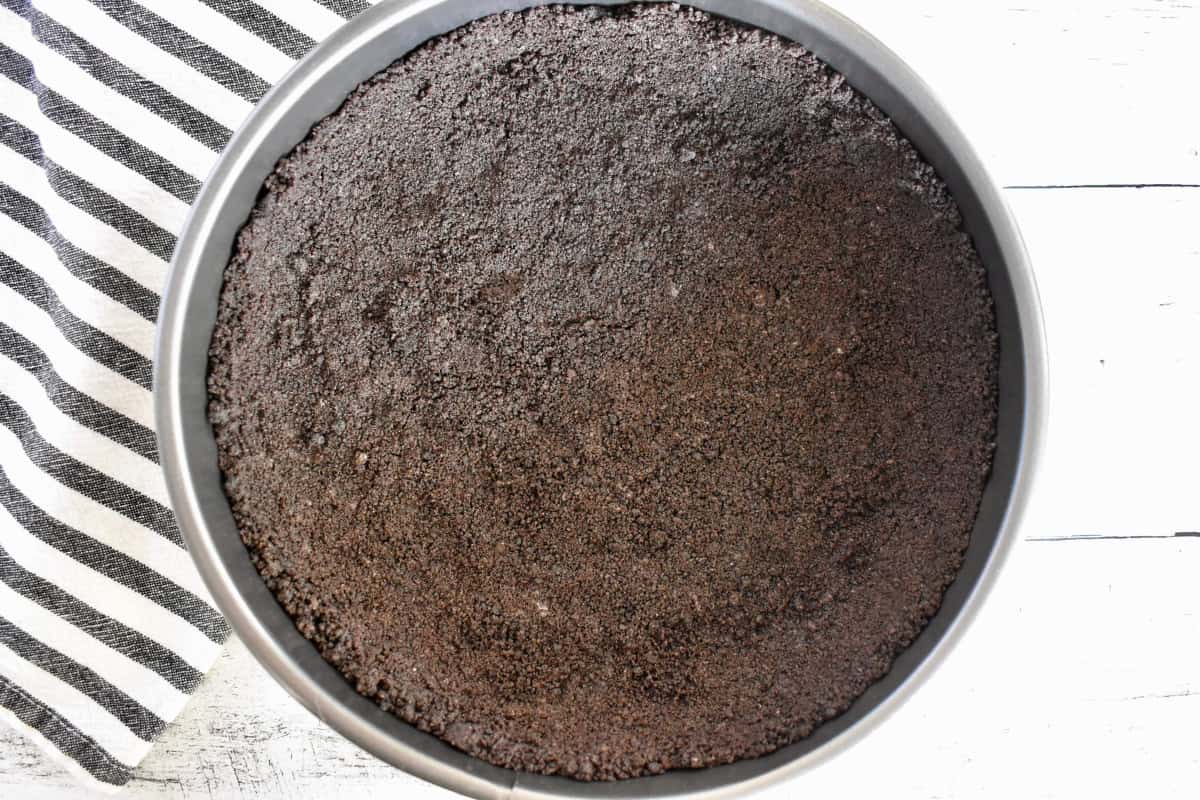 Crushed Oreos pressed into a round springform pan.