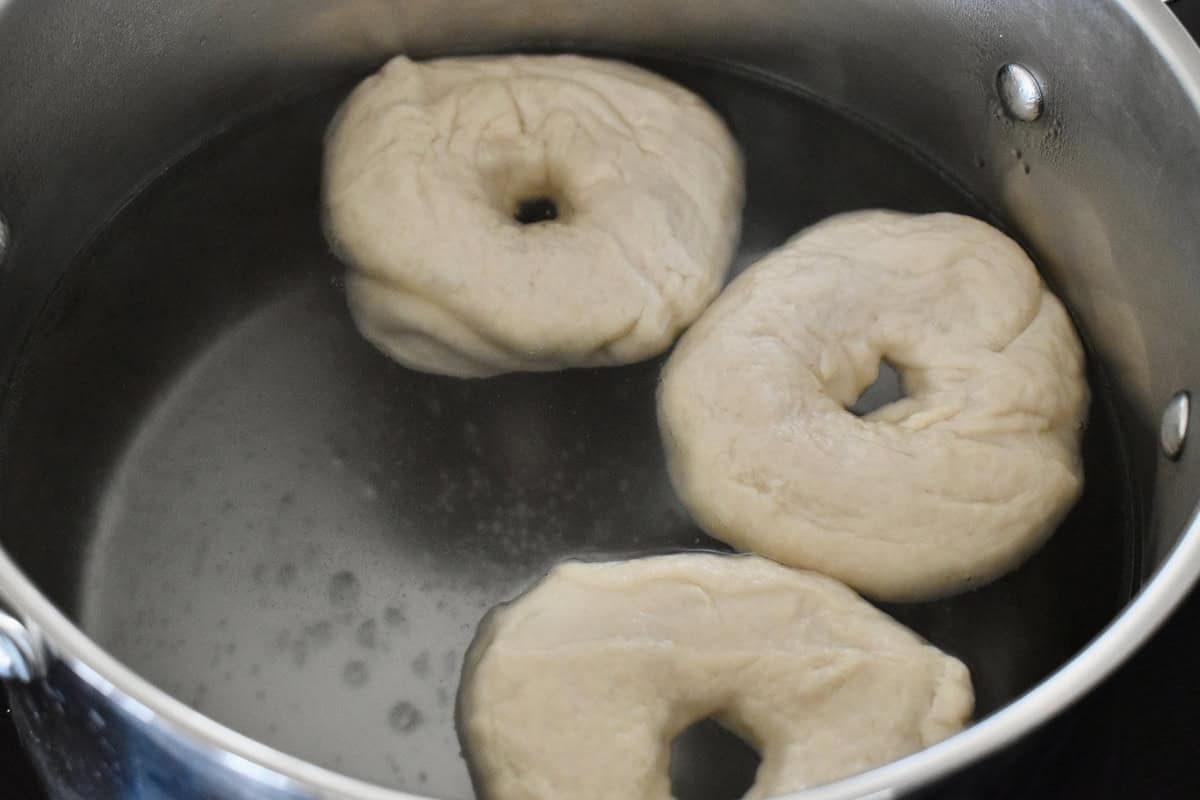 Bagel dough floating in a pot of boiling water. 