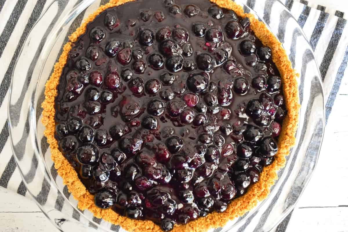 Blueberry pie with graham cracker crust on a countertop. 