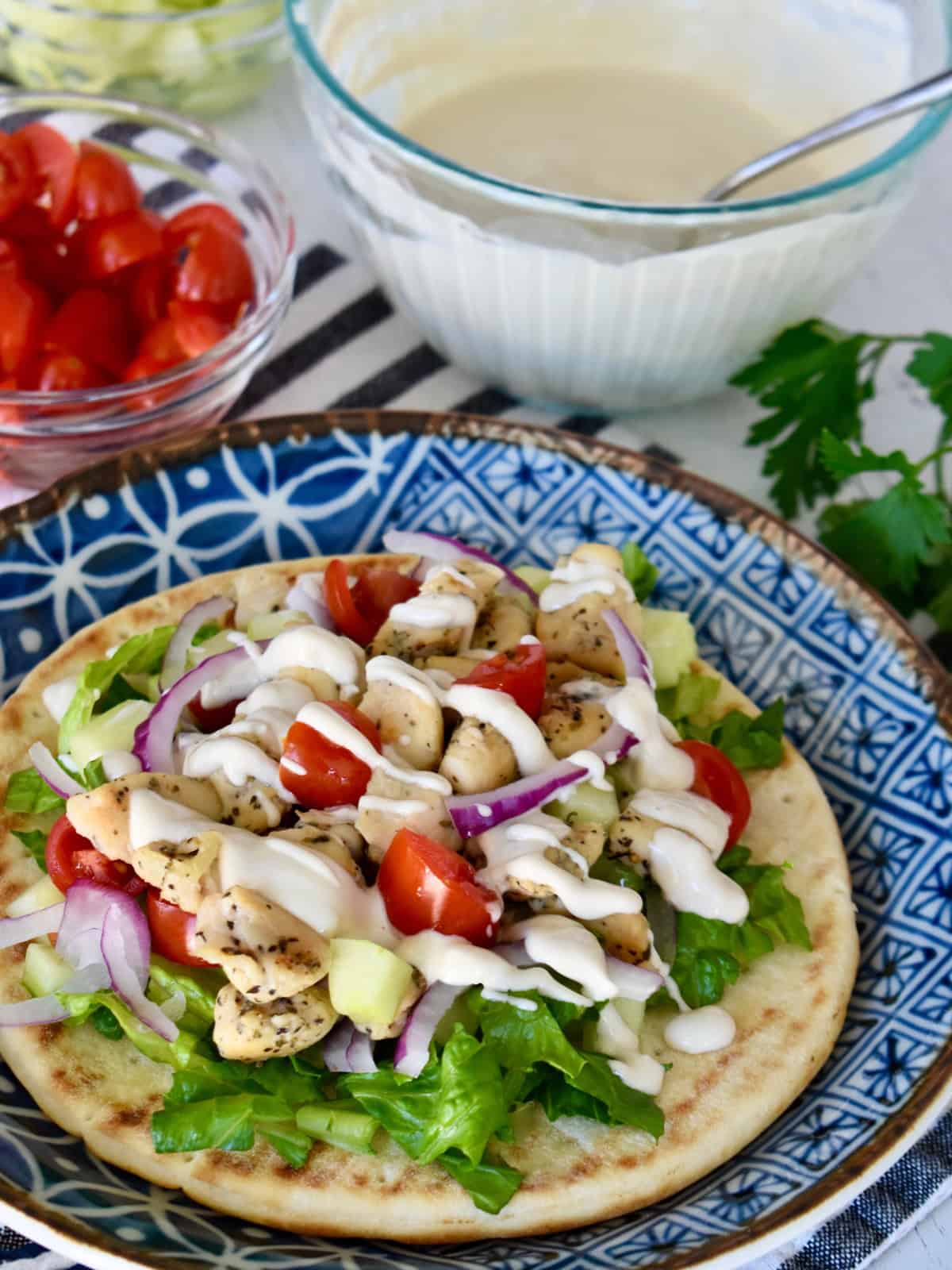 Greek Chicken Pitas on a blue plate with tahini dressing.