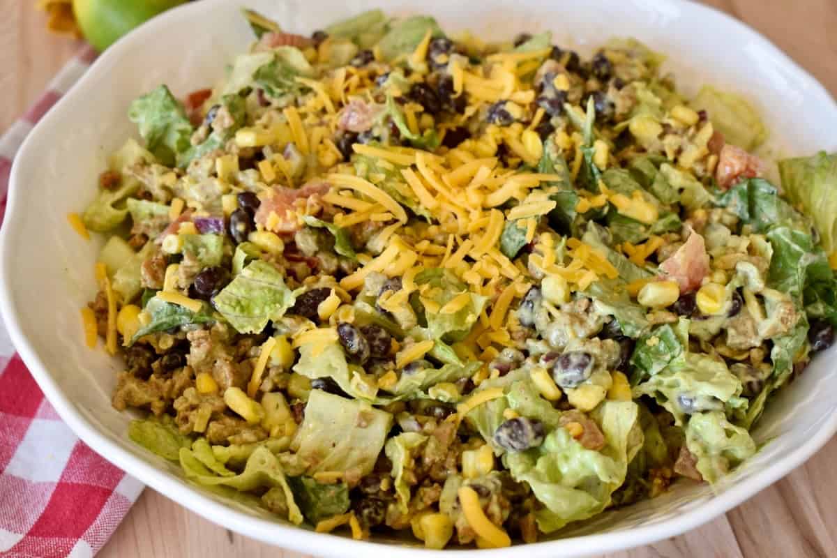 Ground turkey taco salad in a white bowl tossed with a creamy avocado dressing.