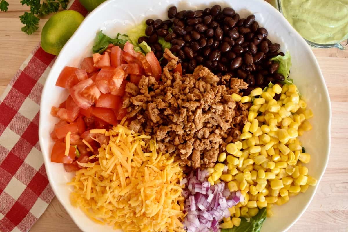 Ingredients for the ground turkey taco salad in a large white bowl.