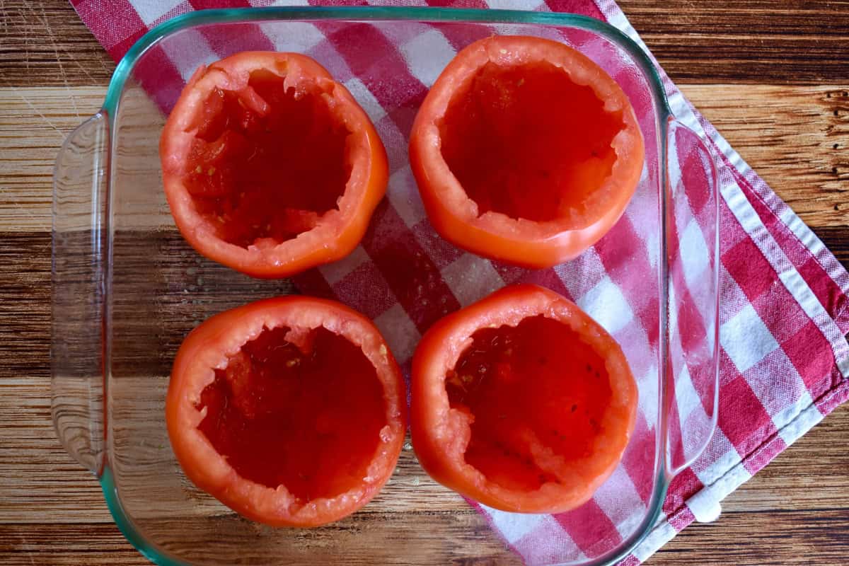Cored tomatoes in a glass baking dish.
